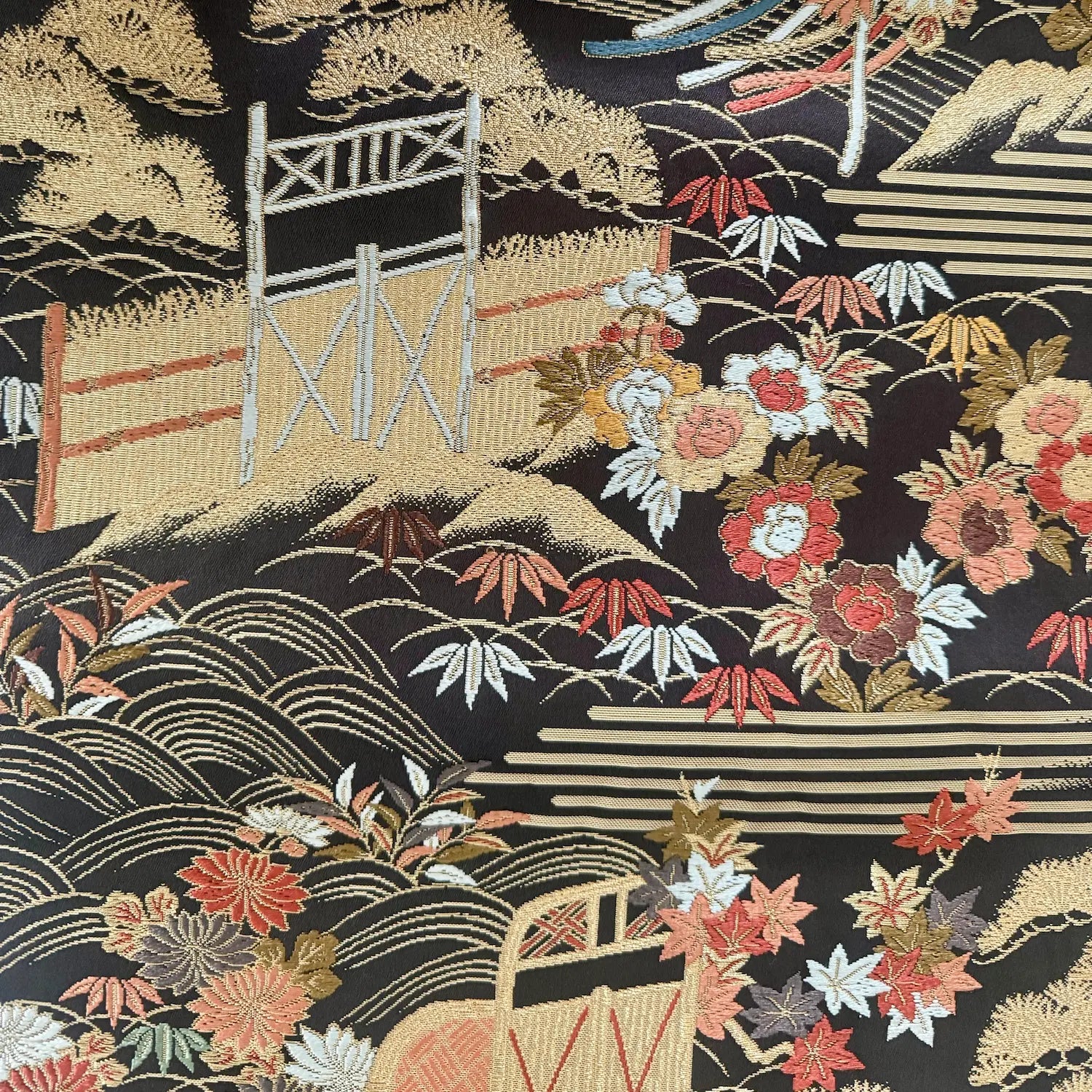 Embroidered fabric with Japanese landscape design featuring a bridge, mountains, and flowers.