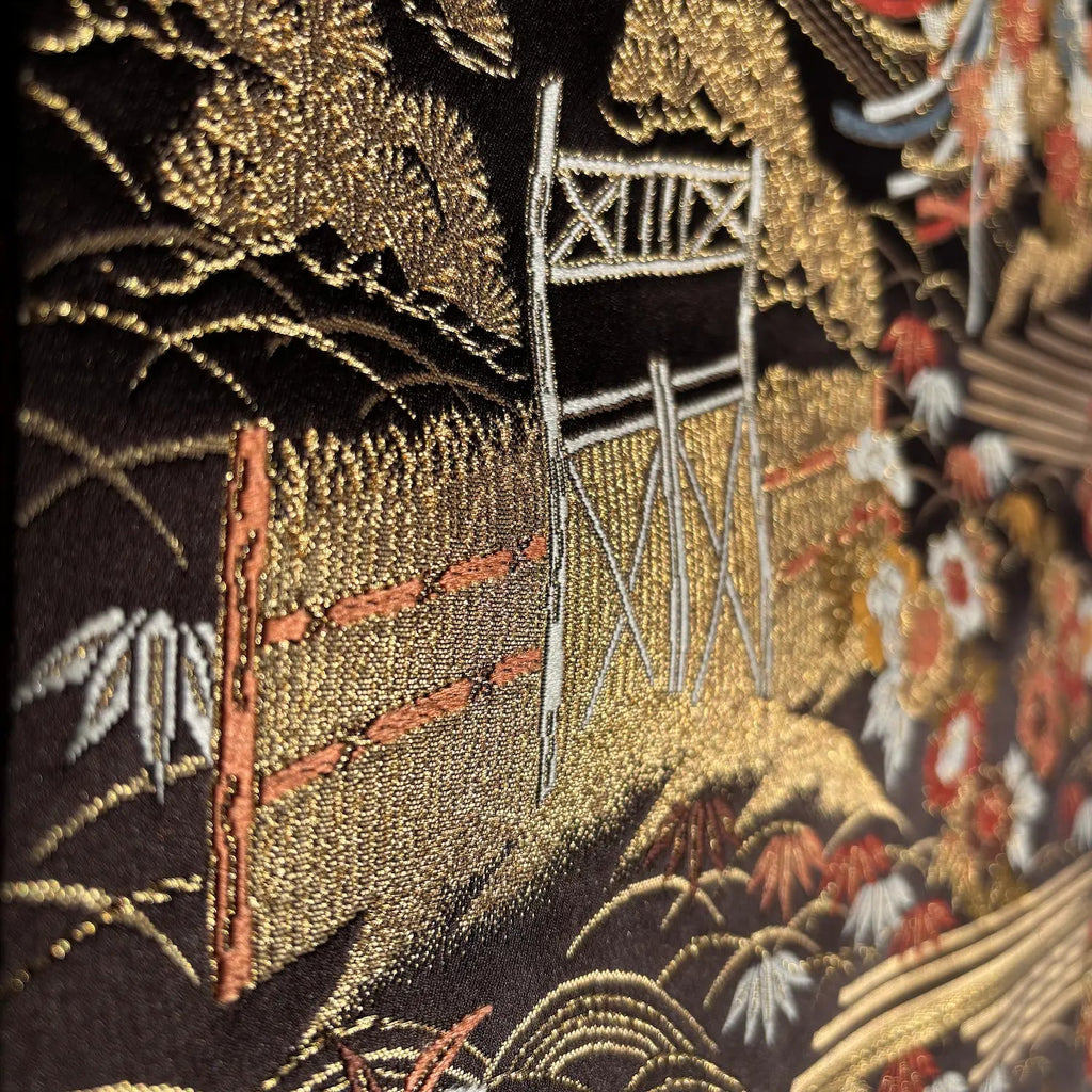 Embroidered scene with a gate and nature elements on a dark background