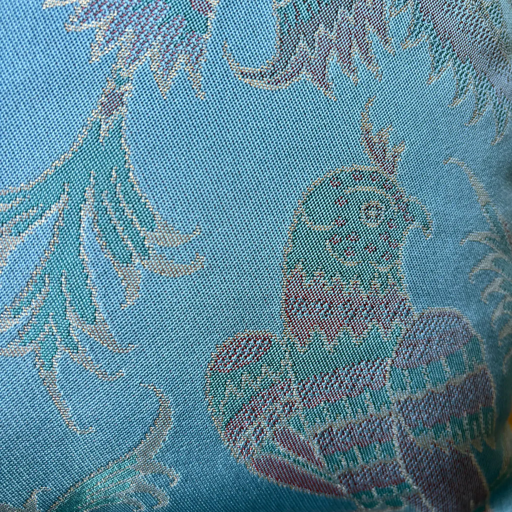 Close-up of a fabric with floral patterns and a phoenix design on a blue background