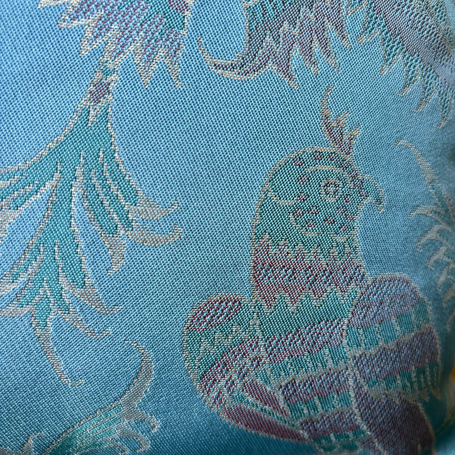 Close-up of a fabric with floral patterns and a phoenix design on a blue background