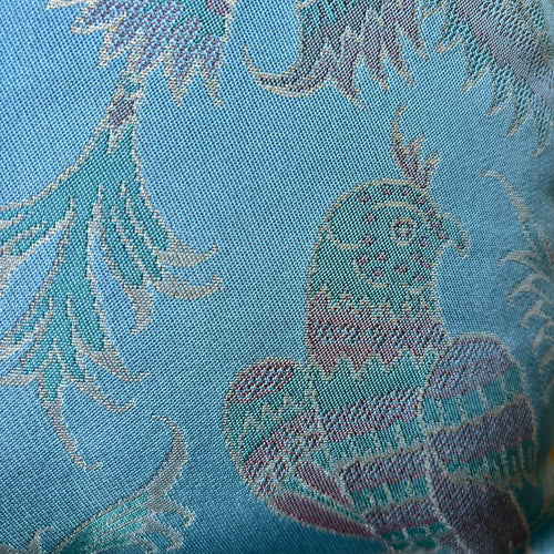 Close-up of a fabric with floral patterns and a phoenix design on a blue background