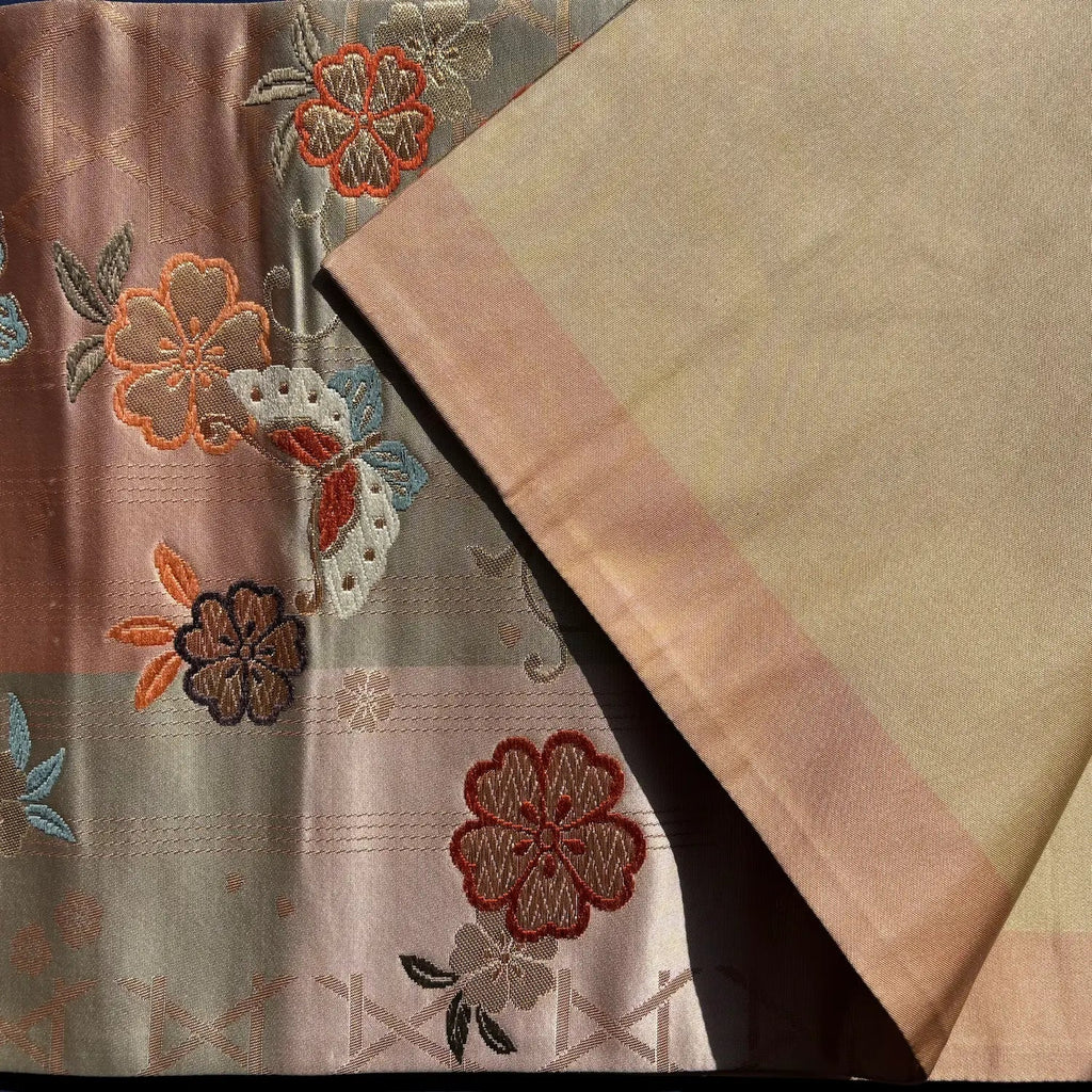 Embroidered fabric with floral patterns in brown, orange, and beige tones.