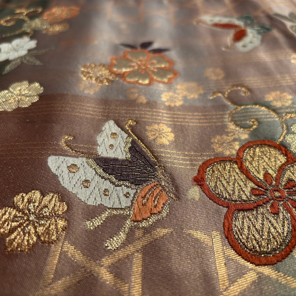 Close-up of embroidered fabric with butterflies and flowers on a brown background