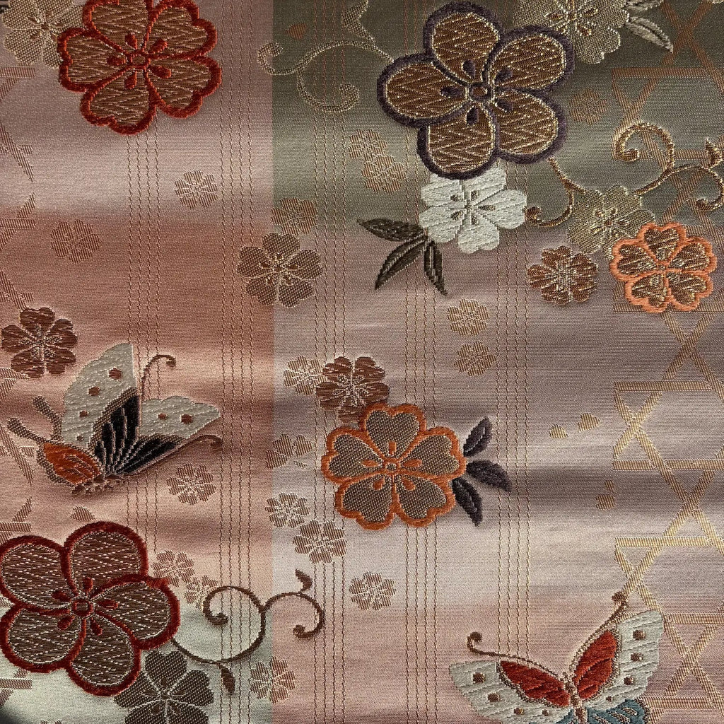 Embroidered fabric with floral and butterfly patterns on a textured background