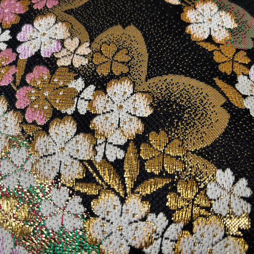 Close-up of a decorative fabric with floral patterns and a mouse design on a black background.
