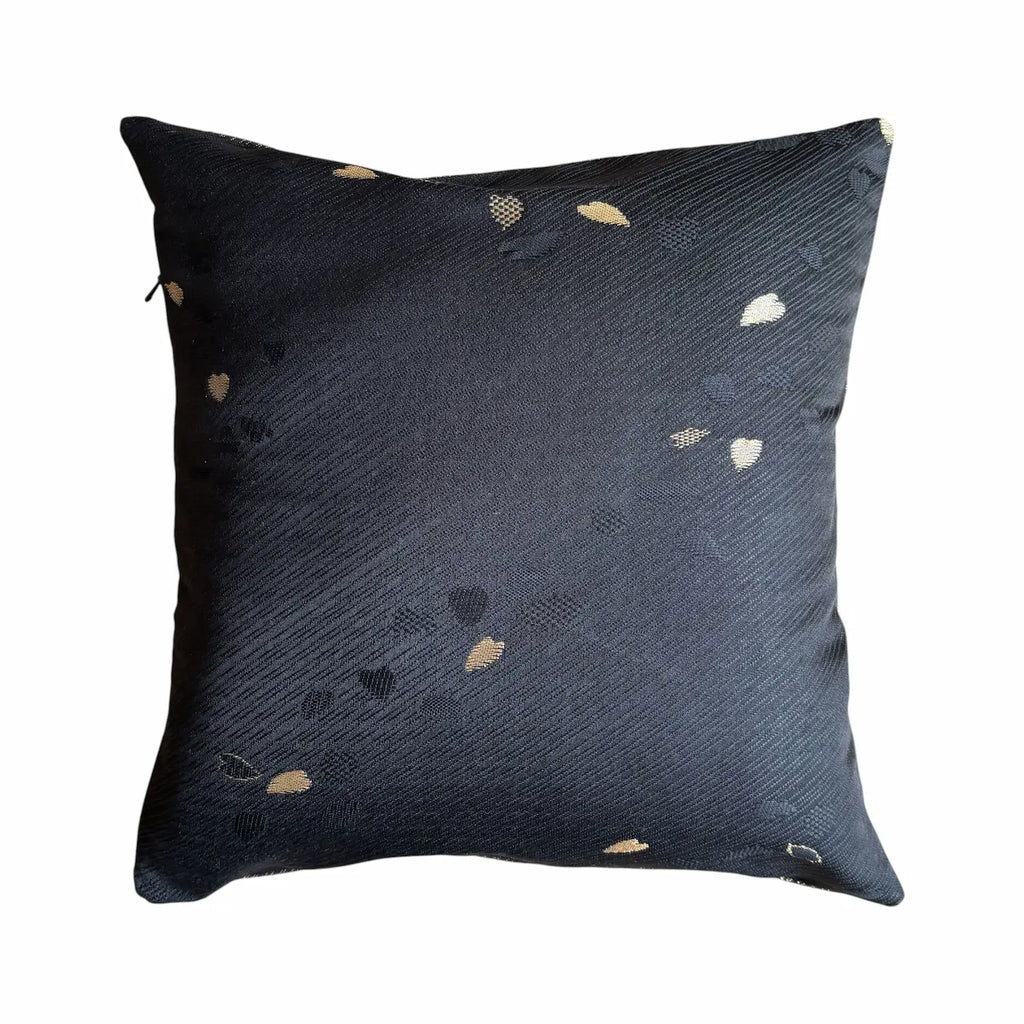 Black cushion with small gold petal patterns on a white background