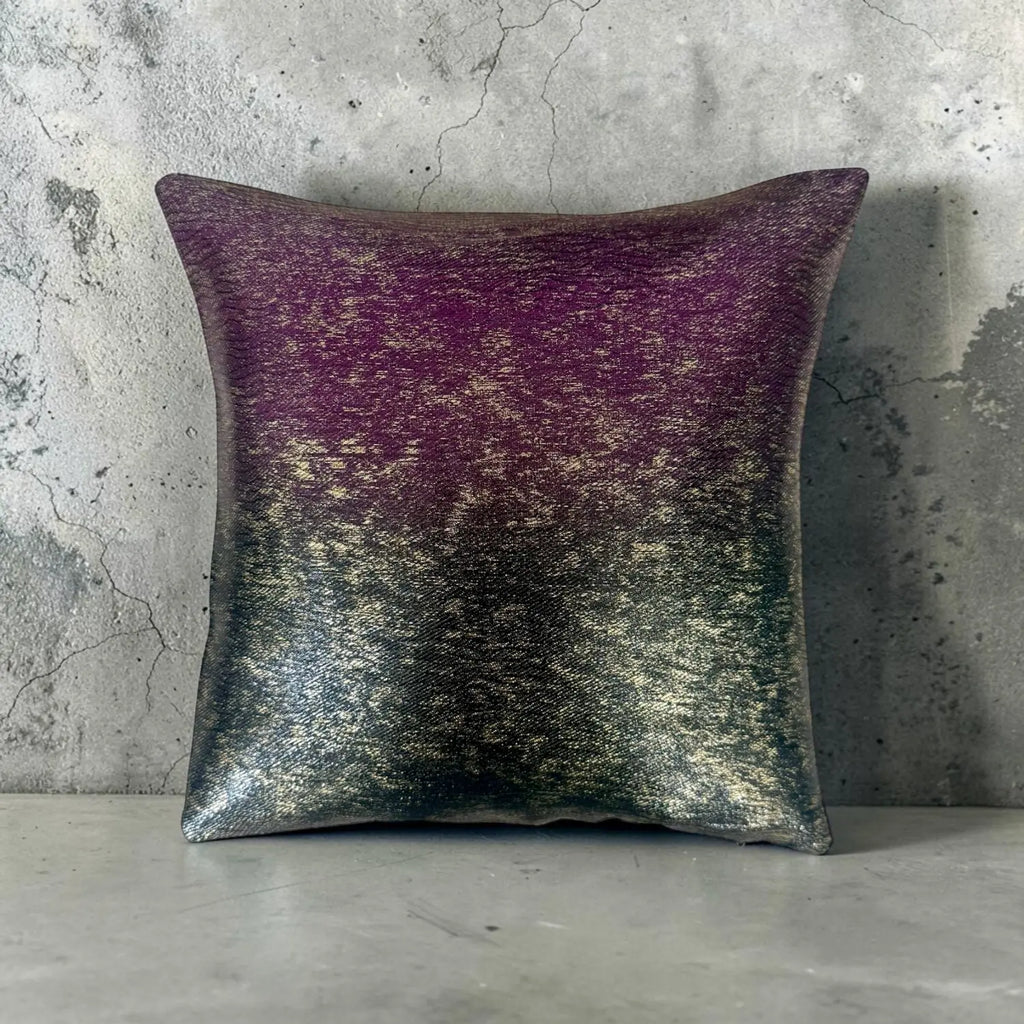 Decorative cushion with gradient purple and green pattern on a concrete wall background