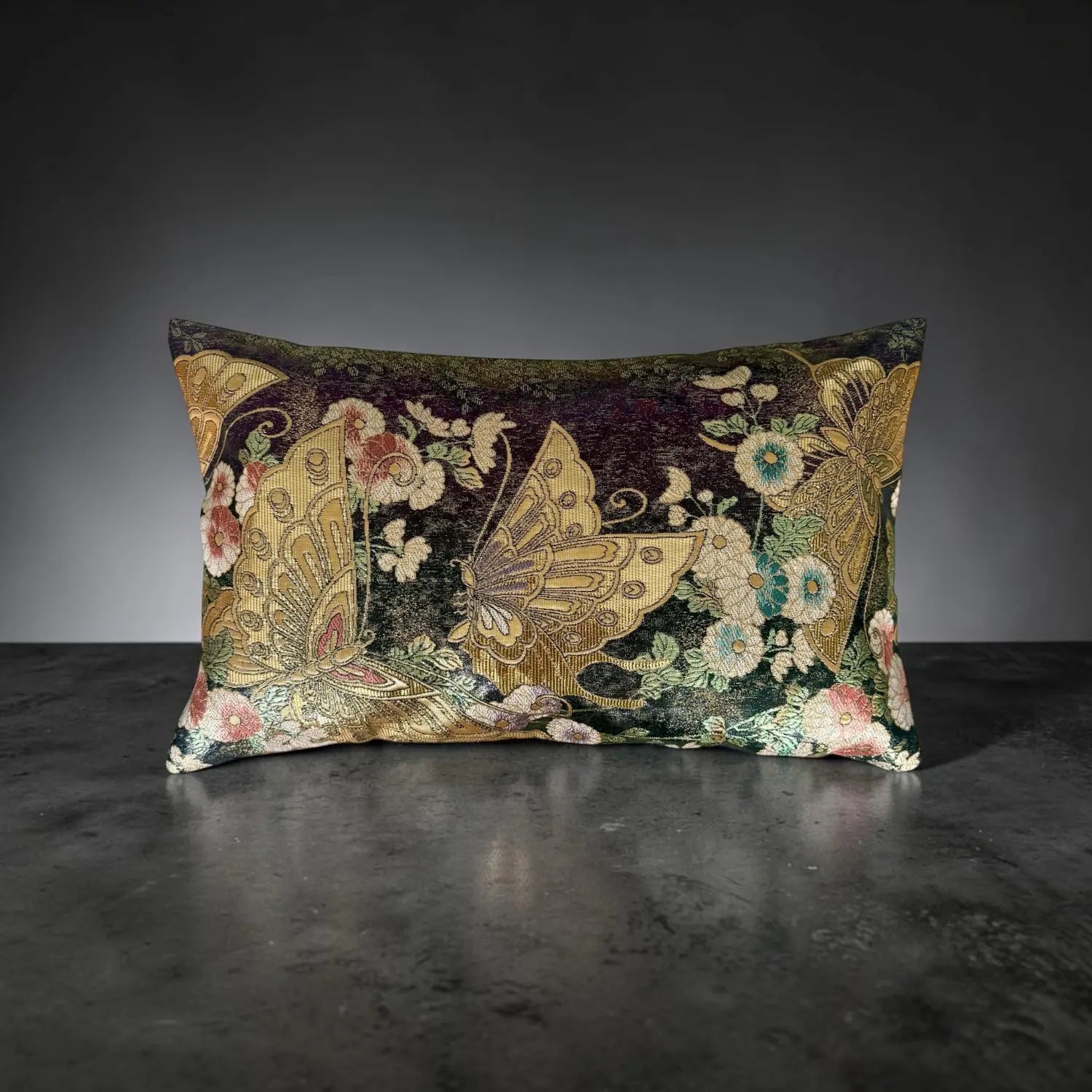 Decorative cushion with floral and butterfly pattern on a dark surface