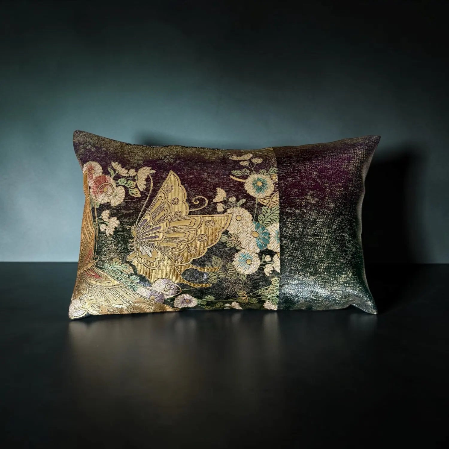 Decorative cushion with floral and butterfly pattern on a dark surface