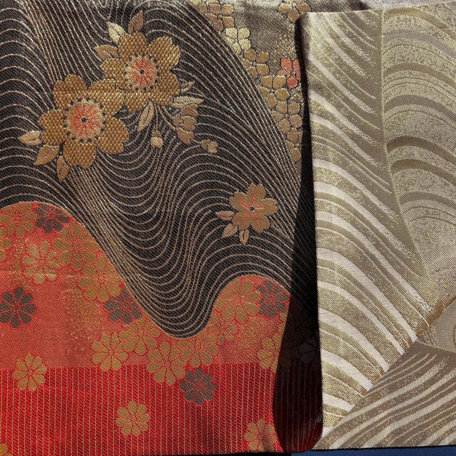 Close-up of a textured fabric with floral patterns in red, gold, and brown.