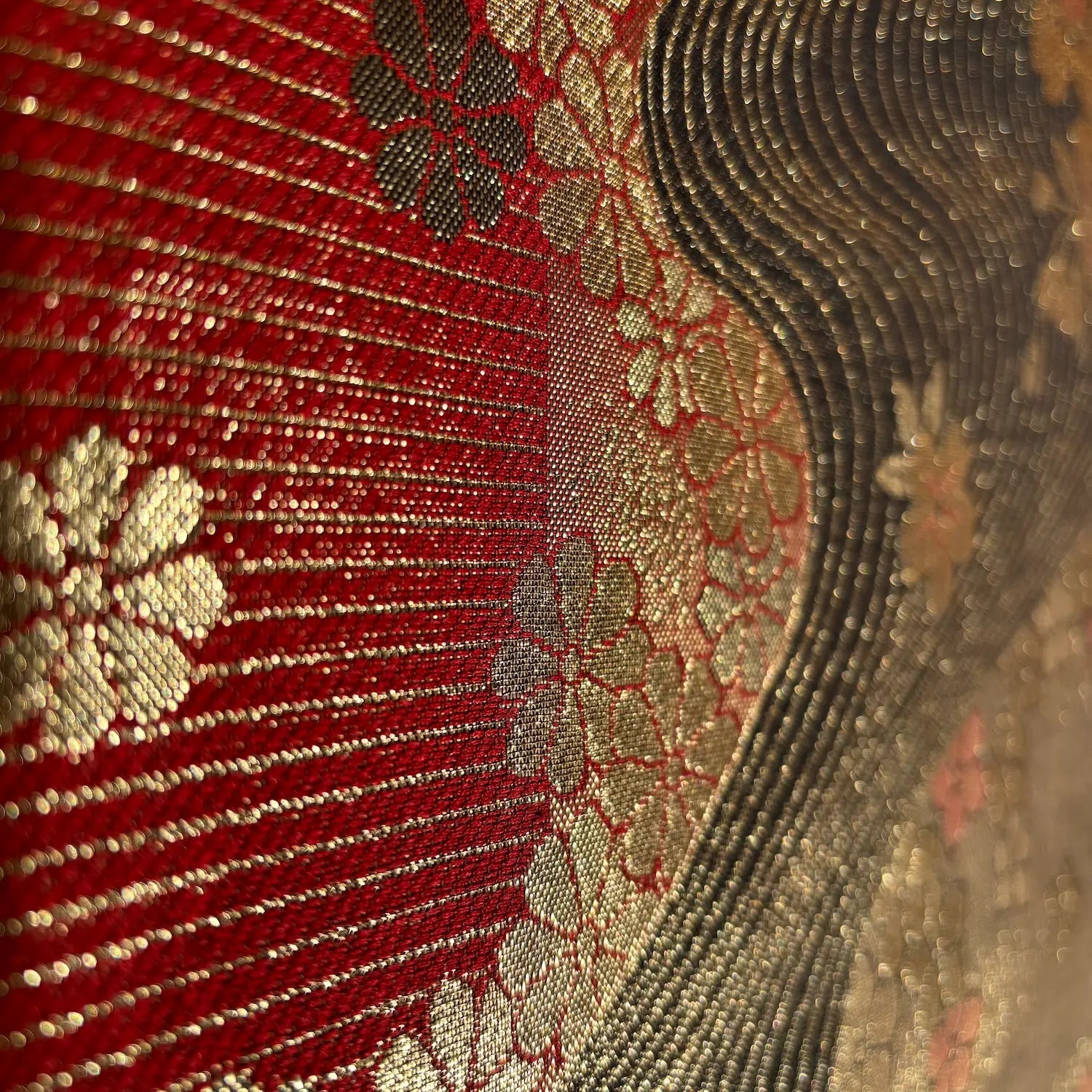 Close-up of a textured fabric with floral patterns in red, gold, and beige.
