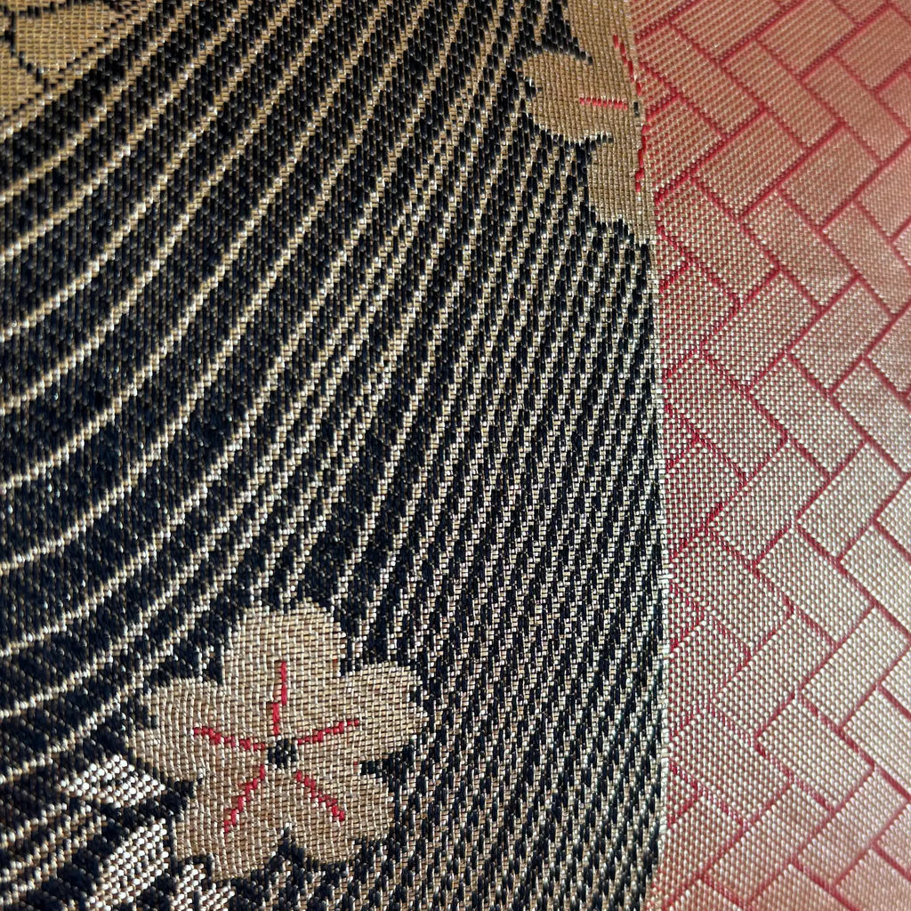 Close-up of textured fabric with floral patterns in black, gold, and red.