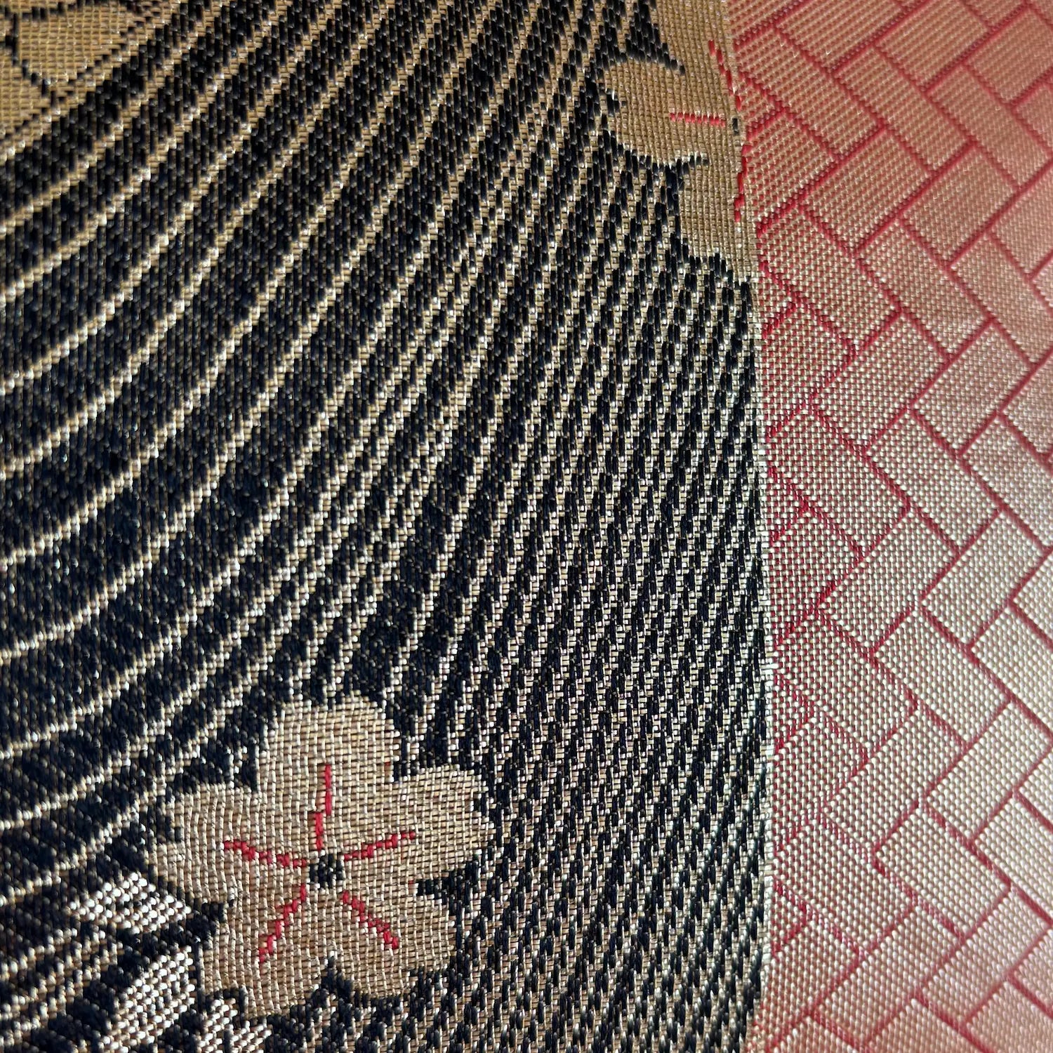 Close-up of textured fabric with floral patterns in black, gold, and red.