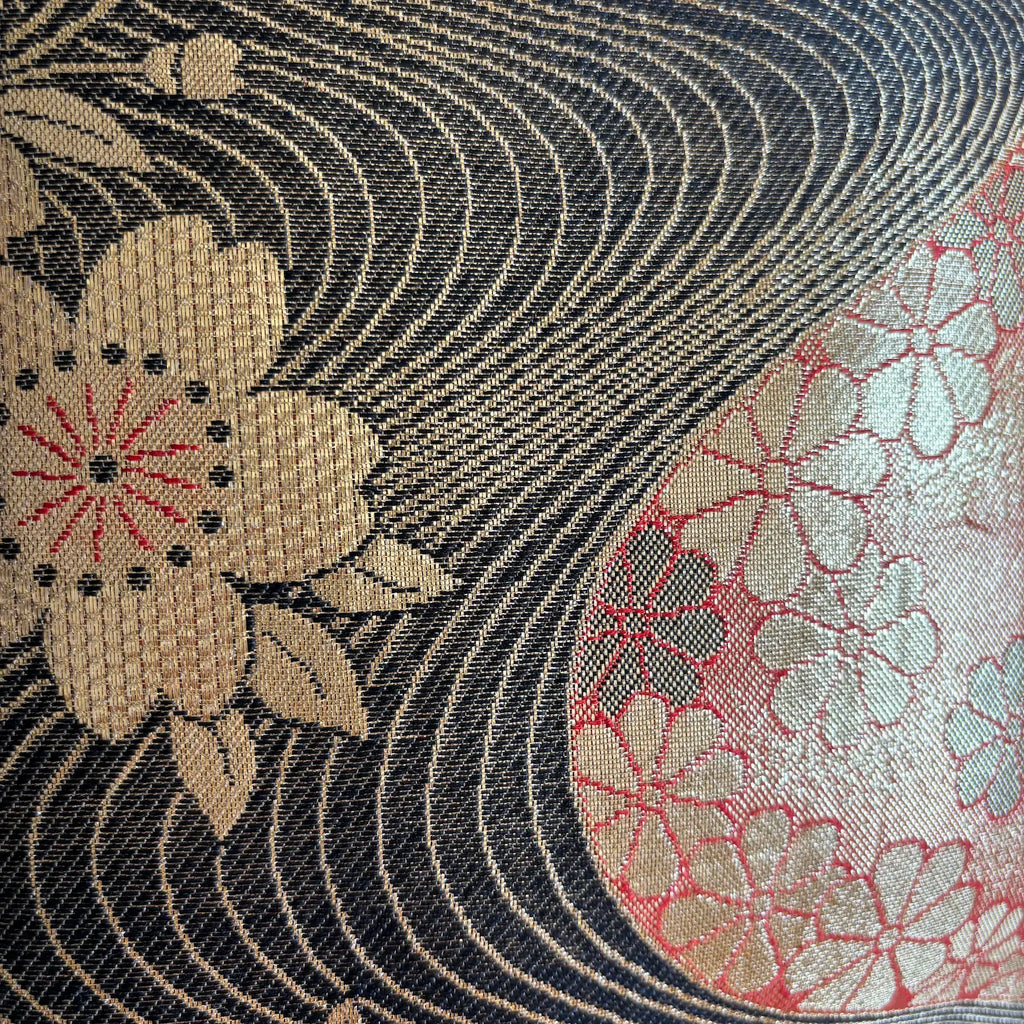 Close-up of floral patterns on fabric with black, gold, and red colours.