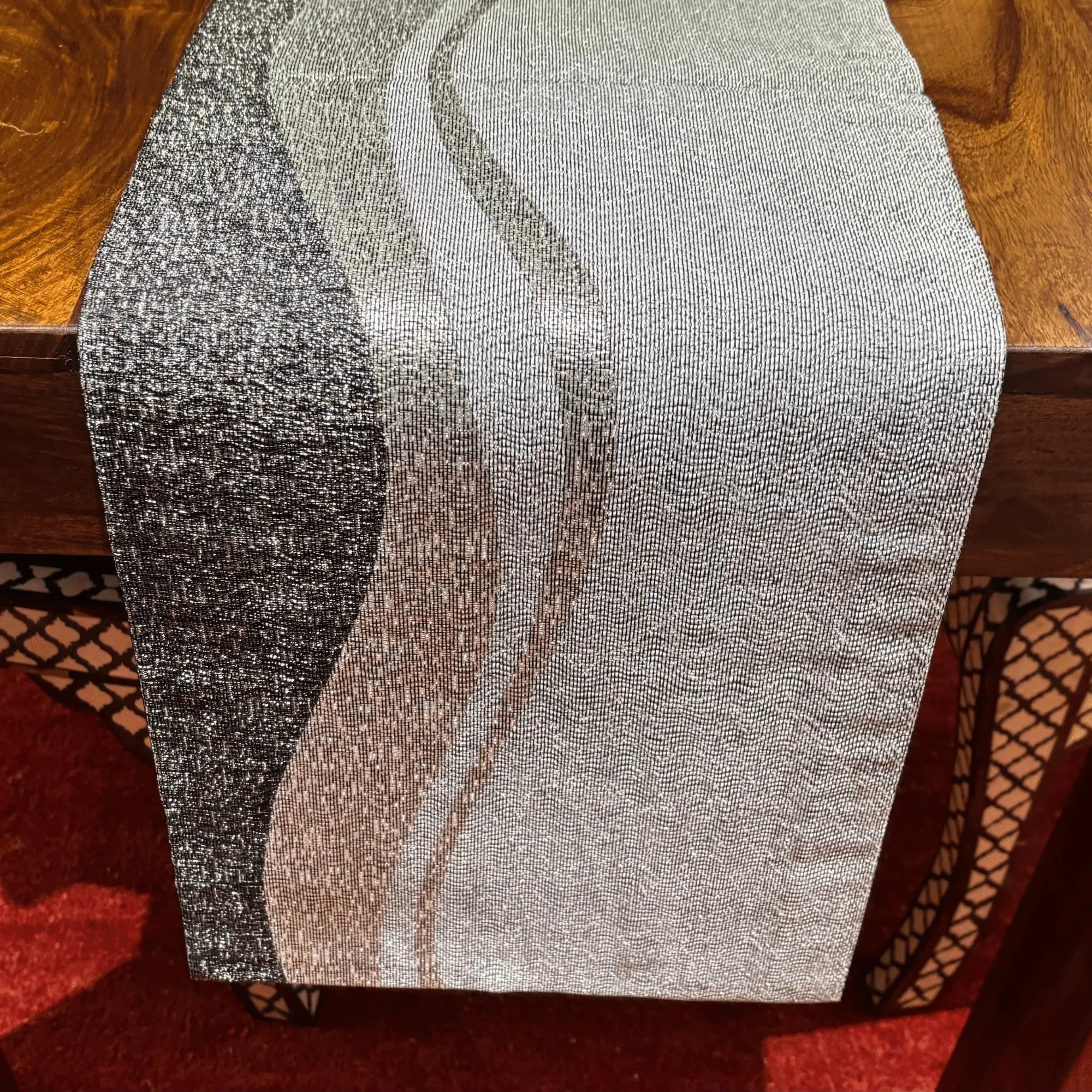 Textured fabric on a wooden surface with a red patterned rug underneath