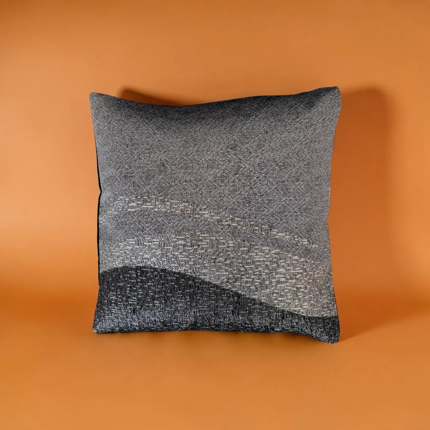 Grey cushion with black base on an orange background