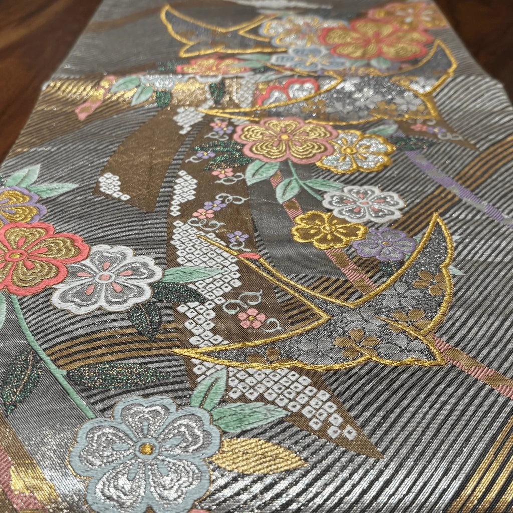 Close-up of a fabric with intricate floral and leaf patterns on a gray background