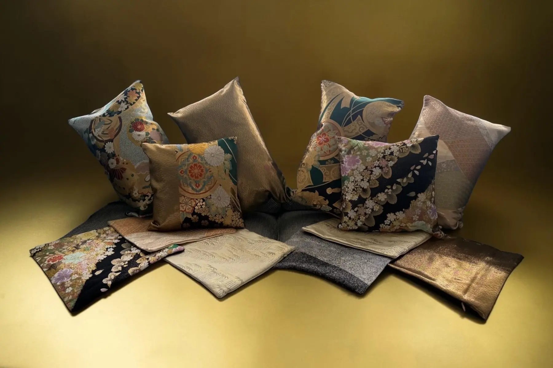 Set of decorative pillows with floral and abstract patterns on a yellow surface.