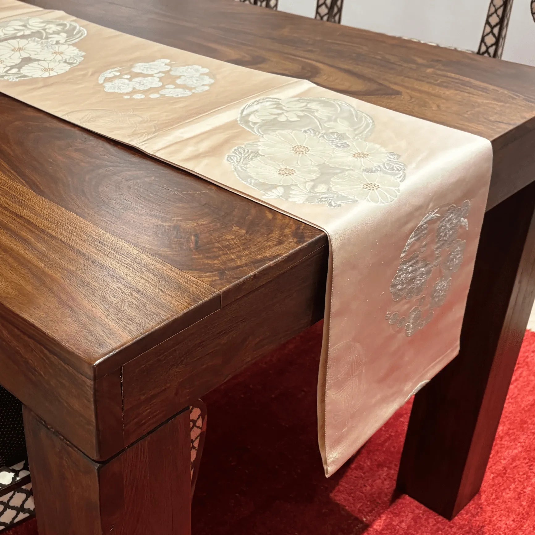 Wooden table with a decorative table runner featuring floral patterns.