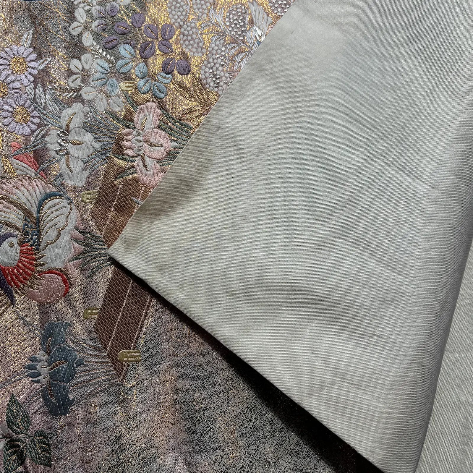 Close-up of embroidered fabric with floral patterns and a plain white fabric.