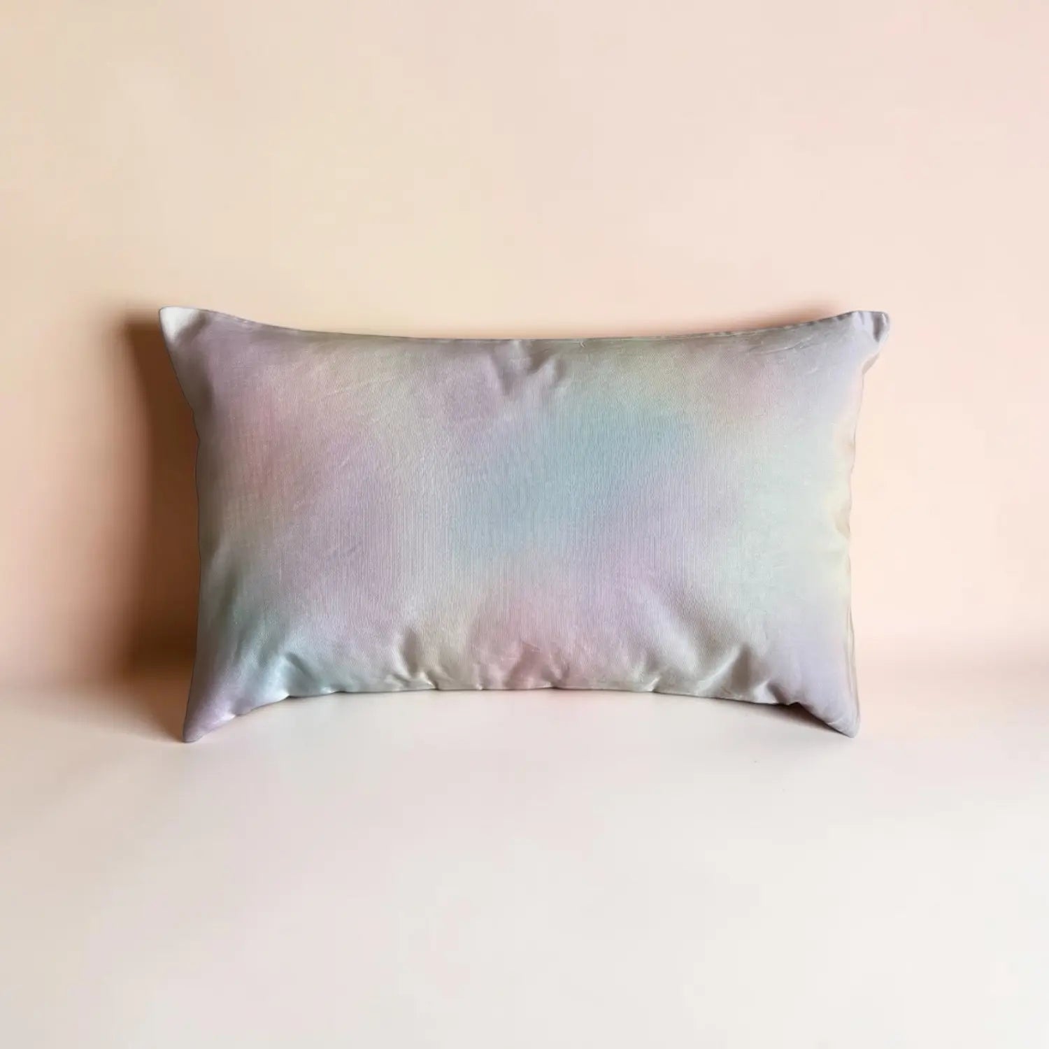 Iridescent satin cushion on a beige background