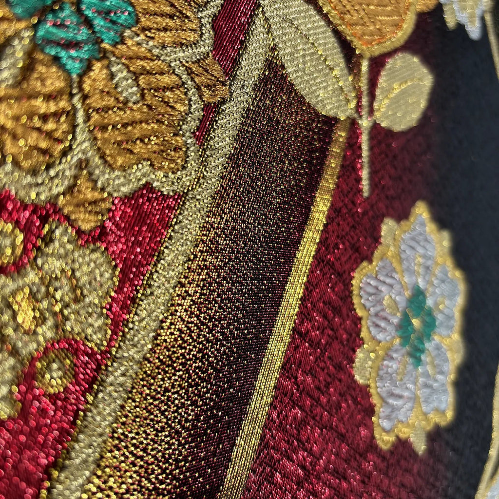 Close-up of embroidered fabric with floral patterns in gold, red, and green.