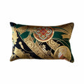 Decorative cushion with intricate gold, green, and red patterns on a white background