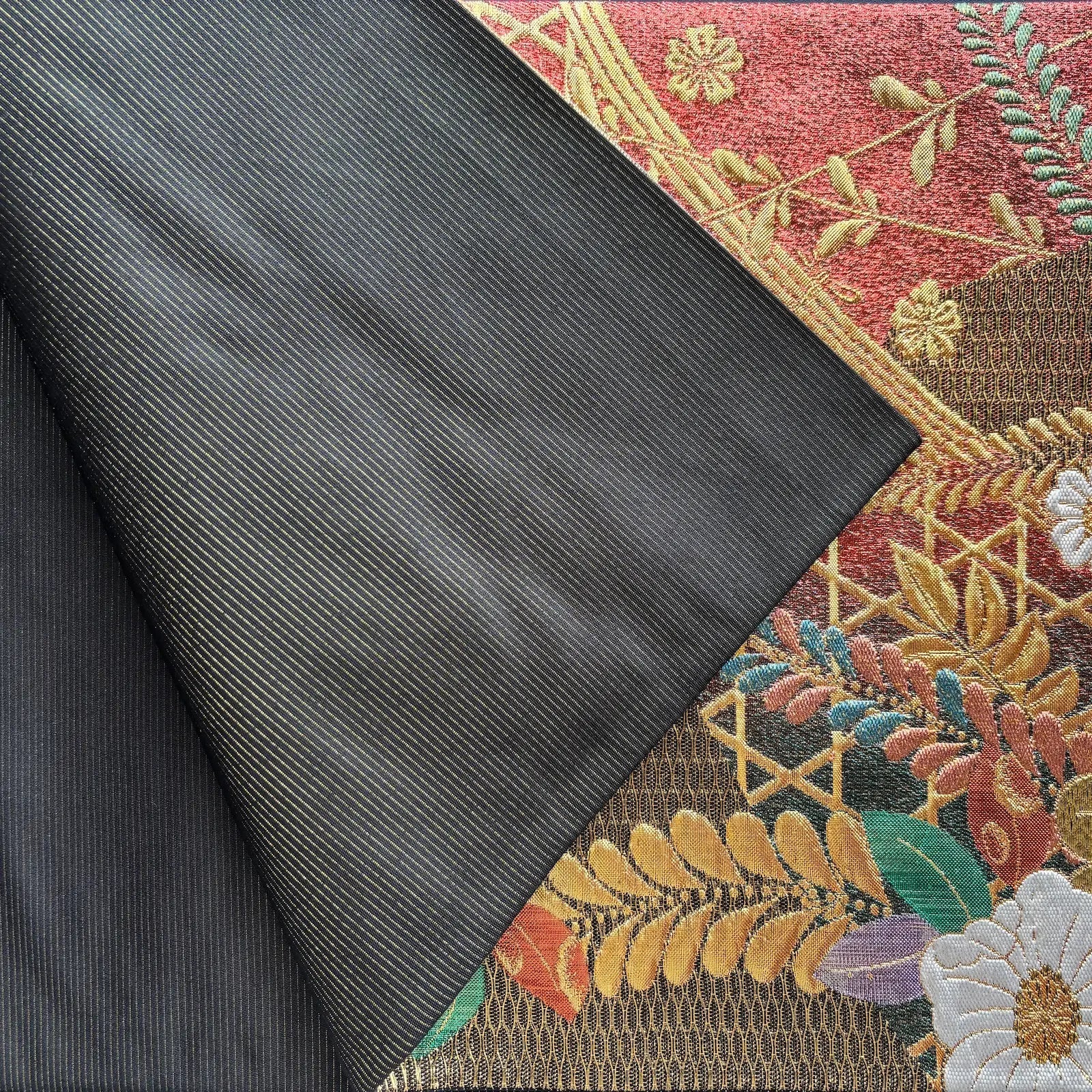 Close-up of textured fabric with floral embroidery and plain dark fabric.
