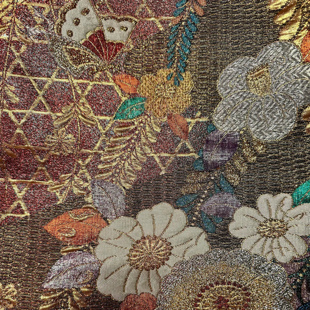 Close-up of intricate floral embroidery with gold thread on a dark fabric background.