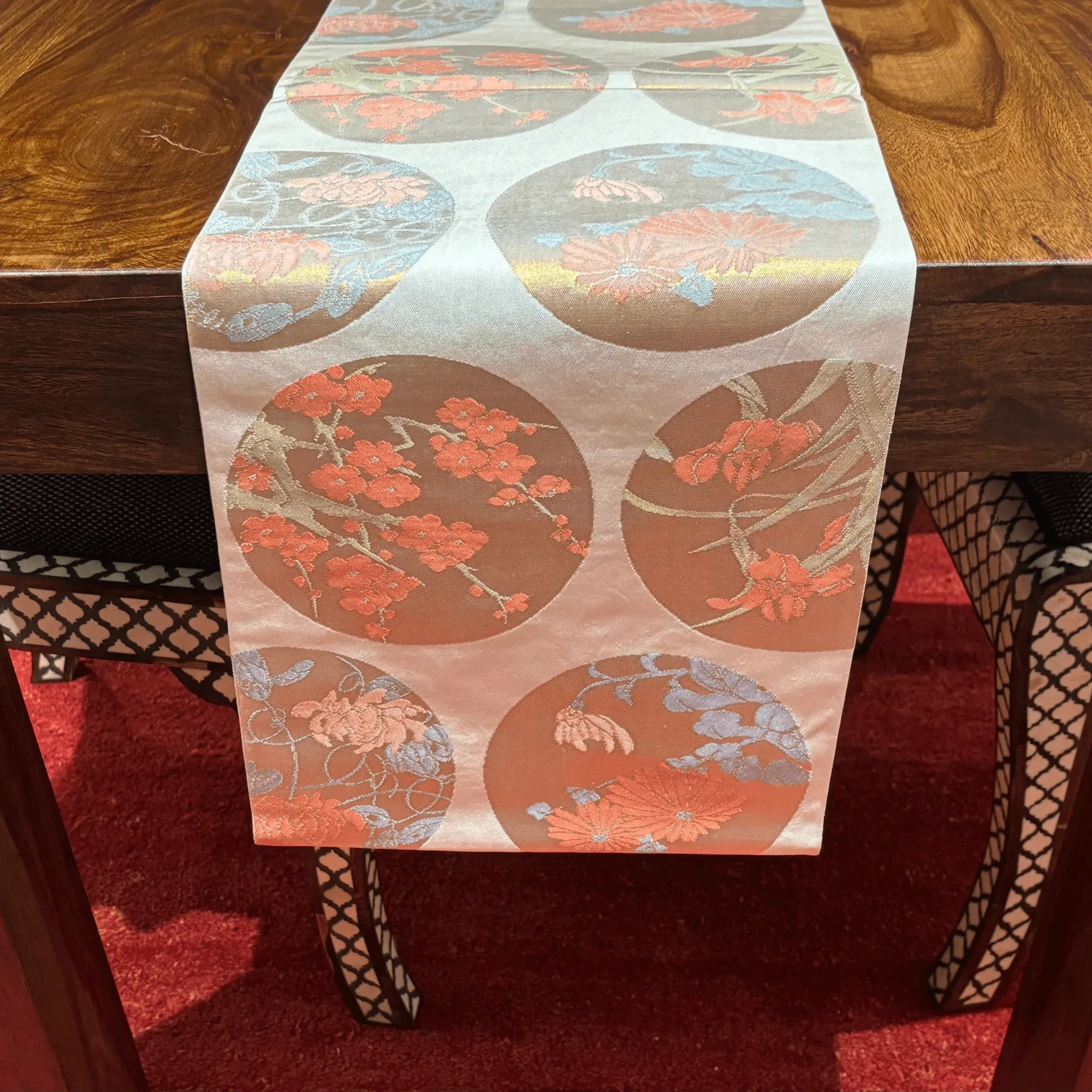 Decorative table runner with floral patterns on a wooden table.