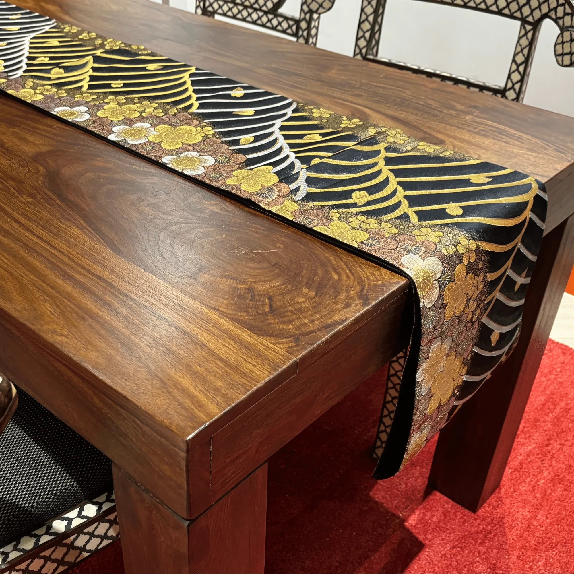 Wooden table with a decorative table runner featuring floral patterns.