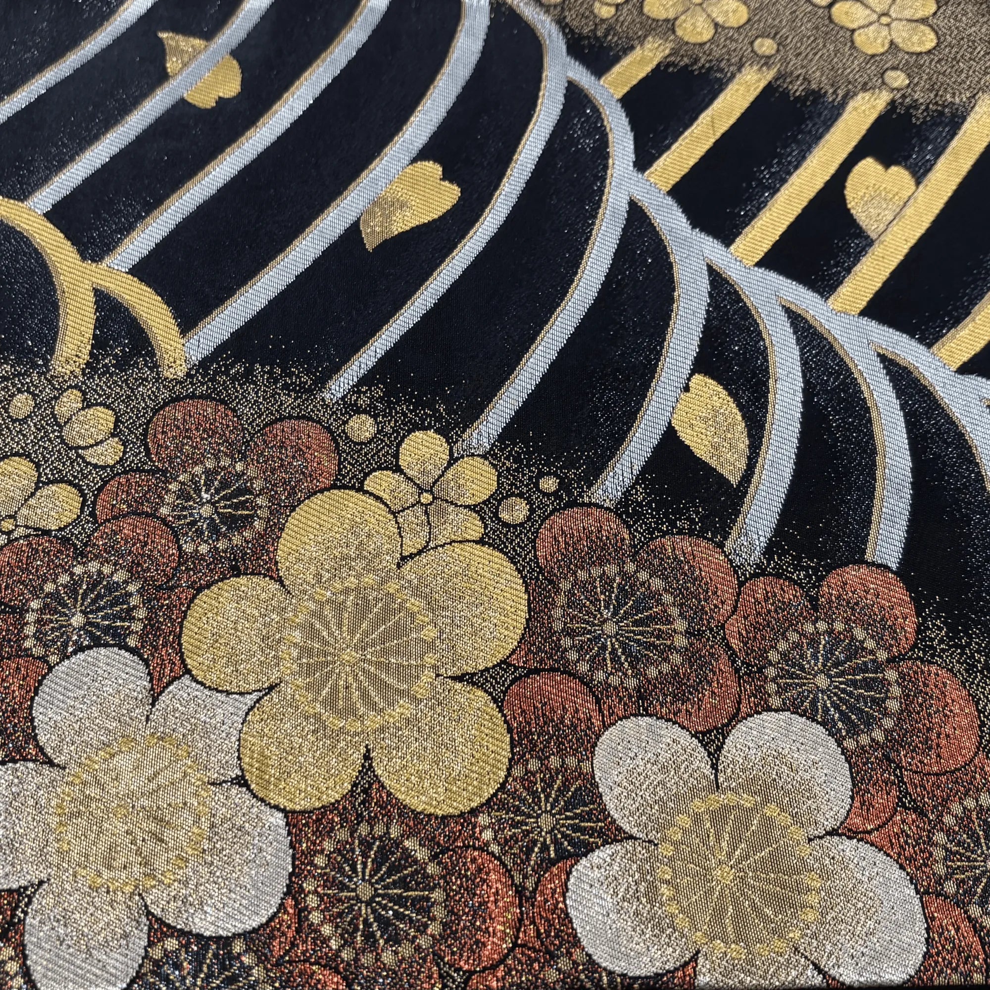 Decorative fabric with floral patterns and metallic accents on a dark background