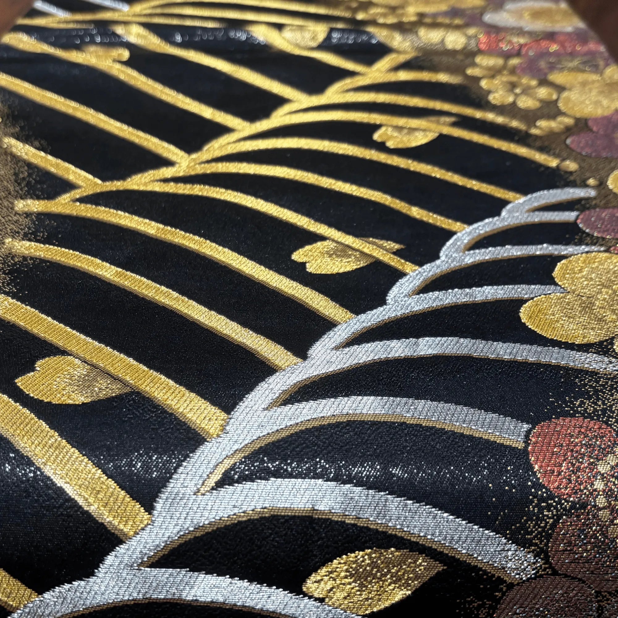 Close-up of embroidered silk with gold and silver patterns on a black background