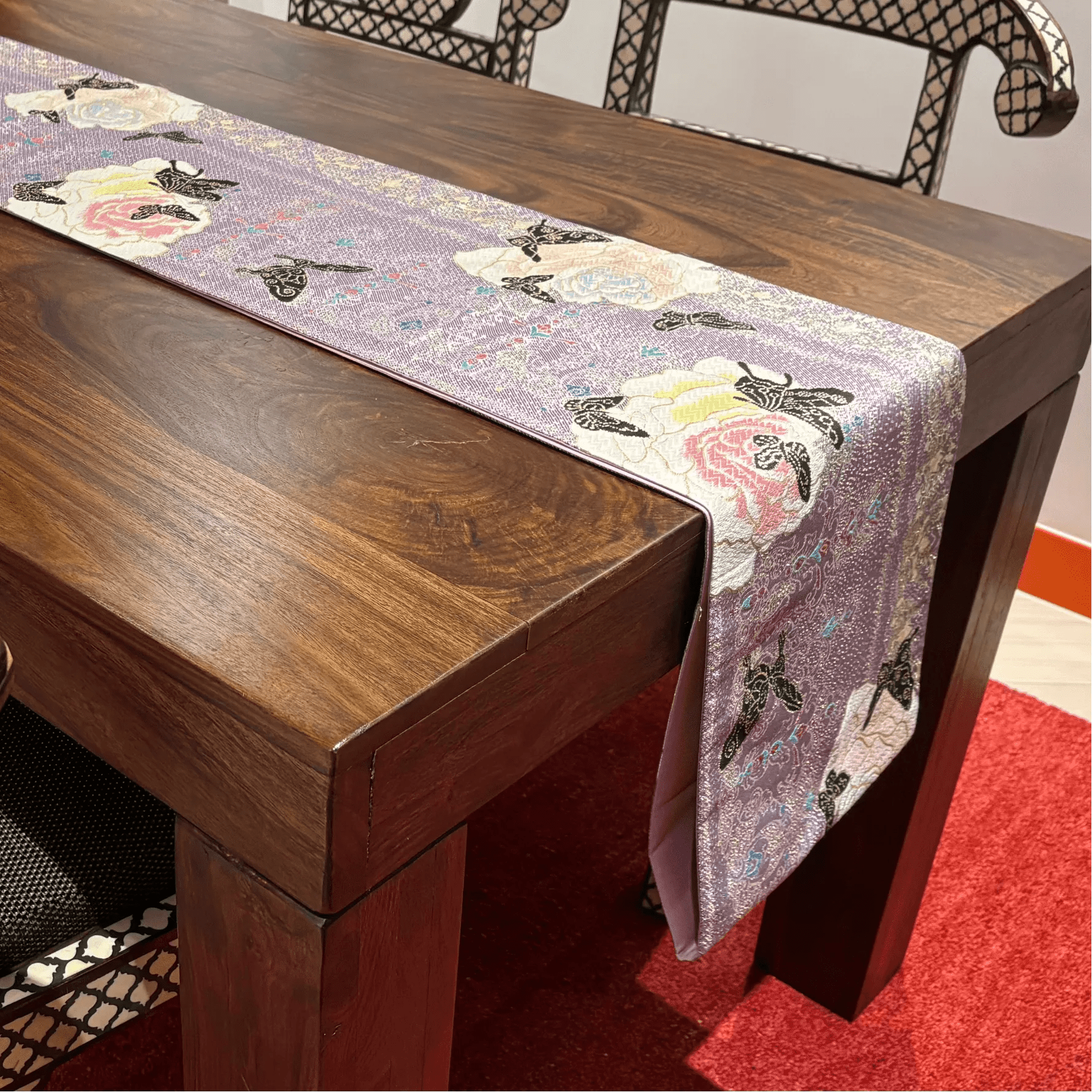 Wooden table with a decorative table runner featuring floral and butterfly patterns.
