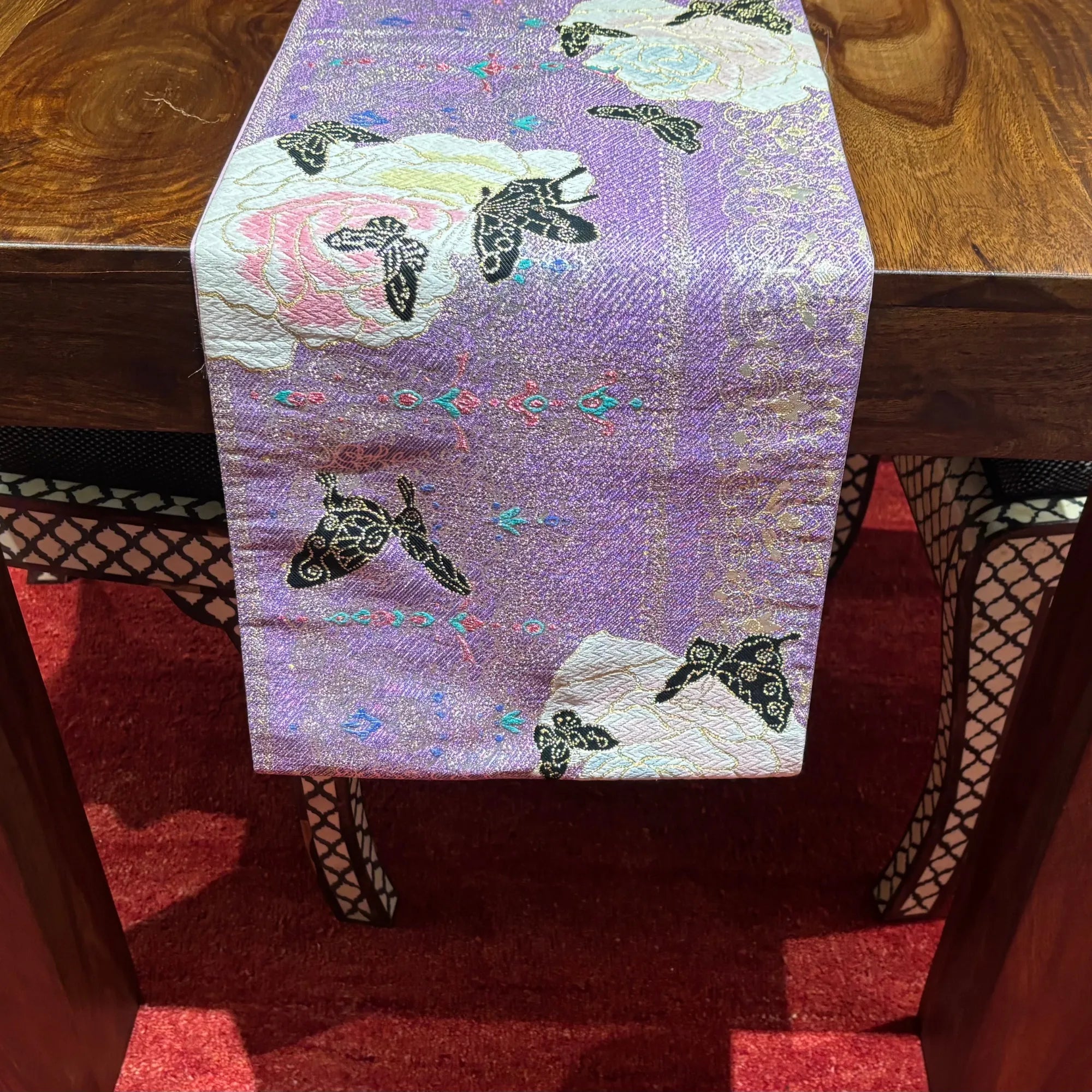 Decorative table runner with butterfly pattern on a wooden table.