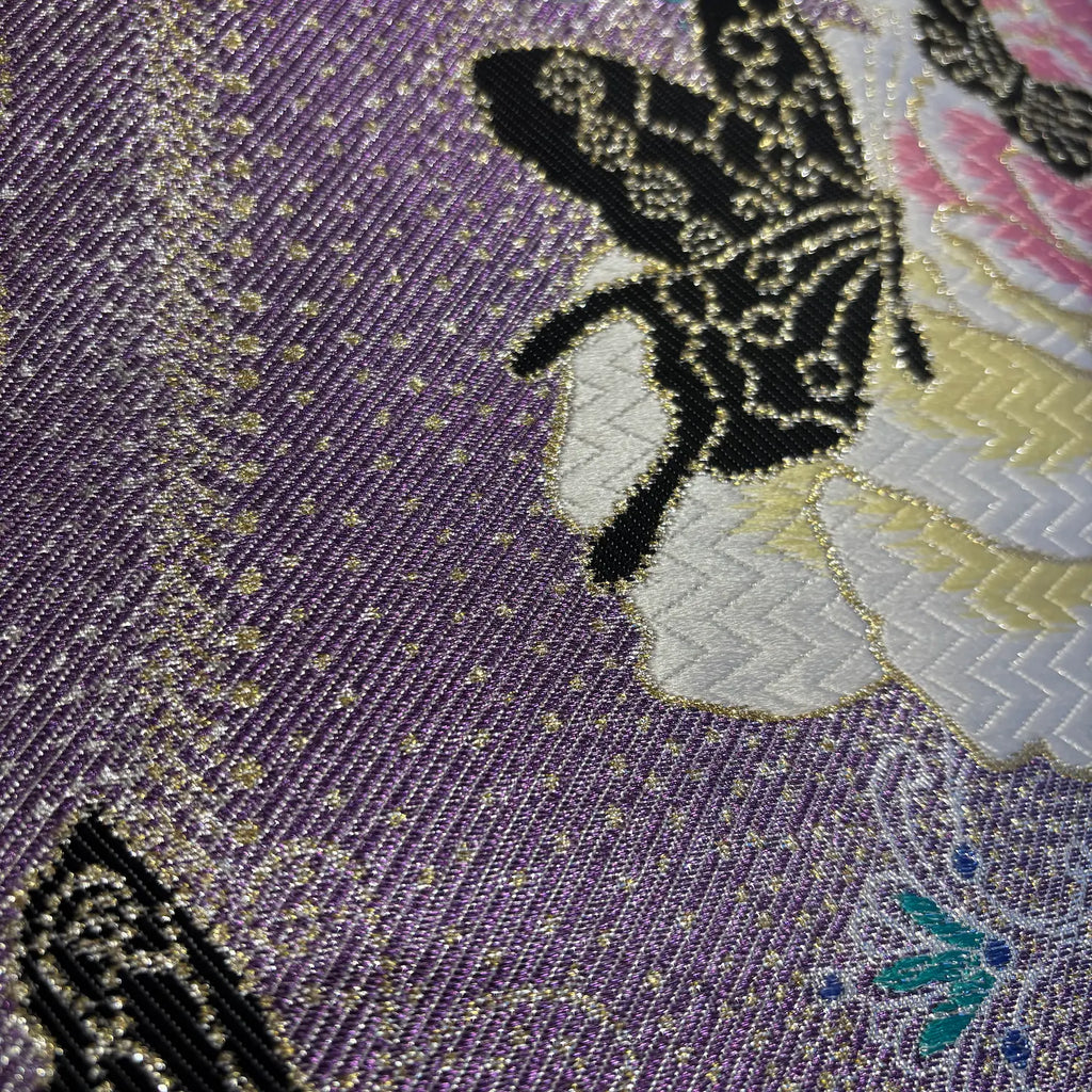 Close-up of embroidered fabric with butterfly design on a purple background