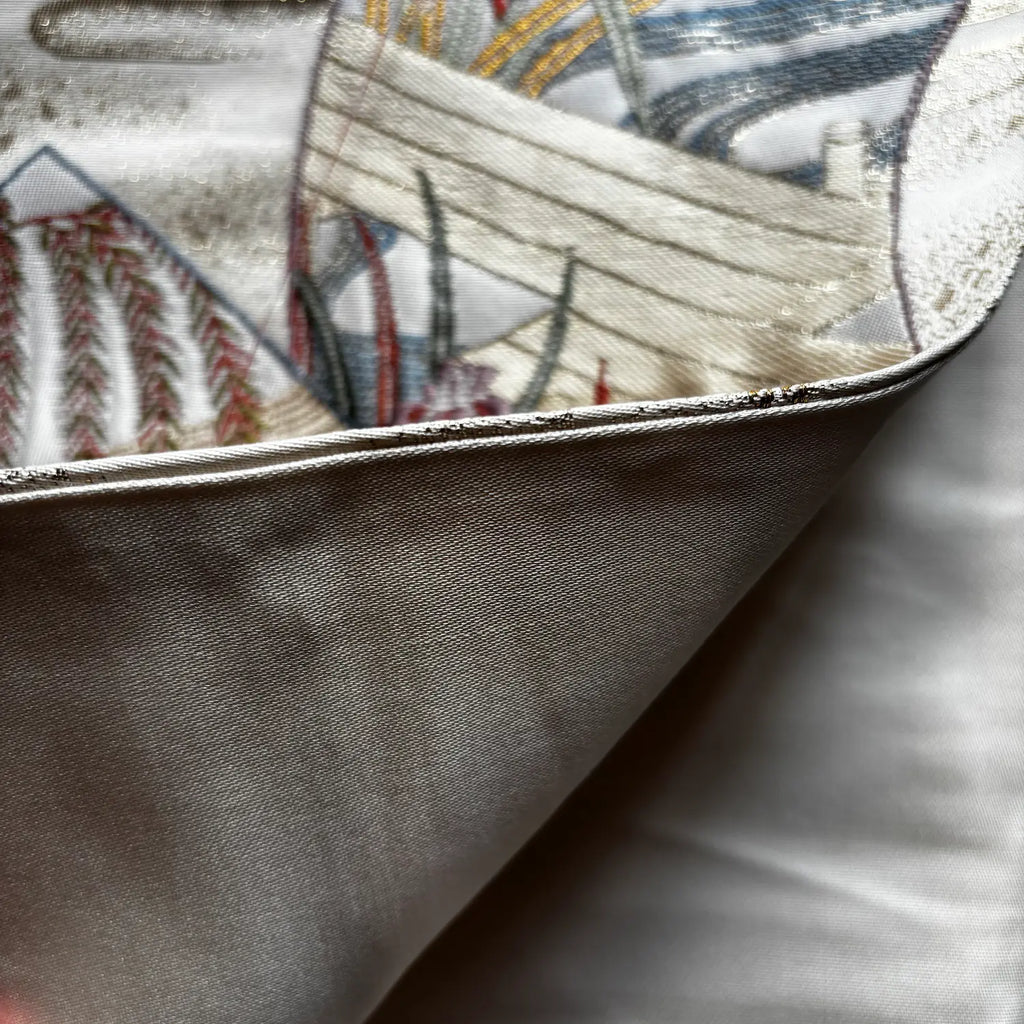 Close-up of a folded Kimono Obi, showing the smooth light gray outer fabric and the printed inner side with a detailed nautical ship design in cream, blue, red, and gray.