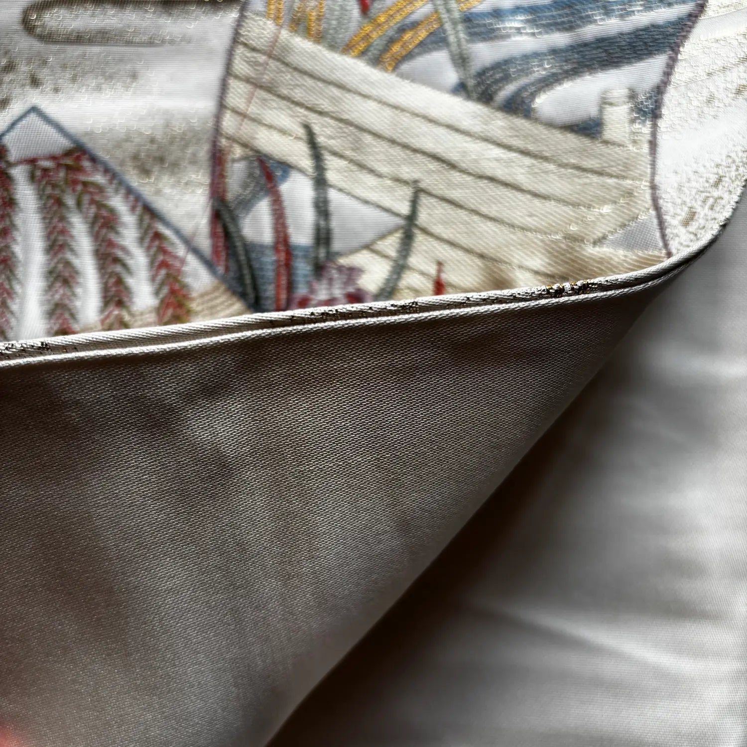 Close-up of a folded Kimono Obi, showing the smooth light gray outer fabric and the printed inner side with a detailed nautical ship design in cream, blue, red, and gray.