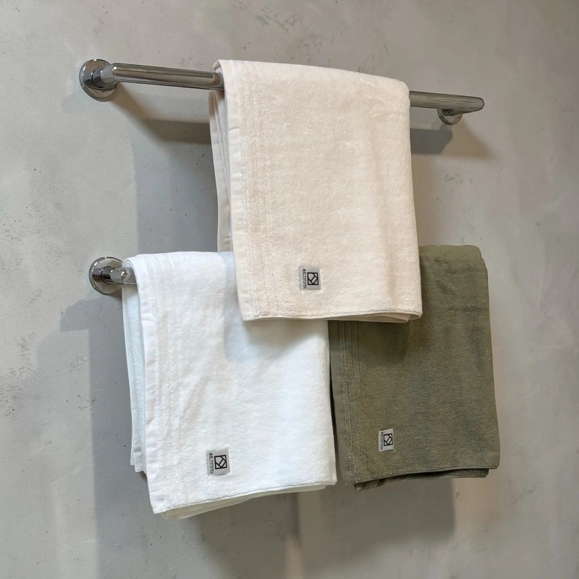 Three Senshu towels Sawa hanging on a towel rack against a neutral wall.
