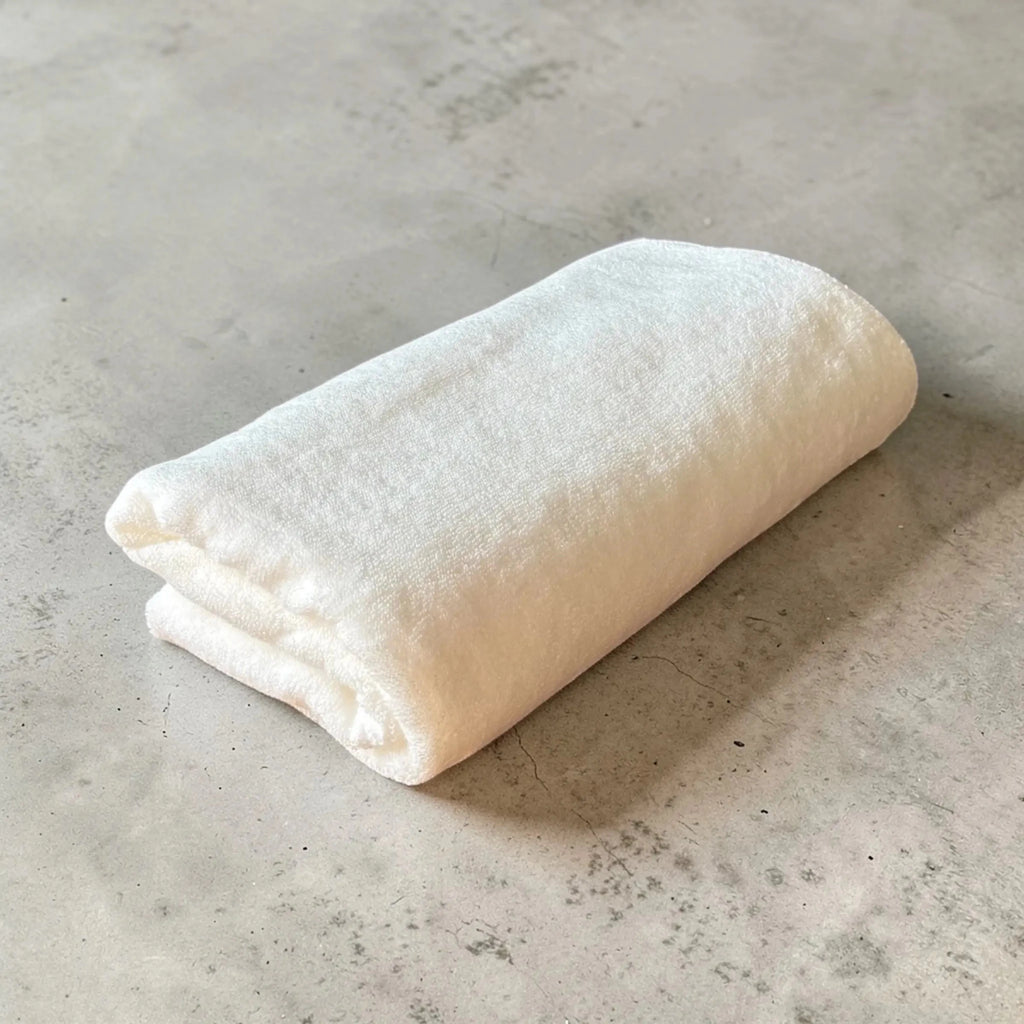 Folded white Senshu bath towel Sawa on a textured gray surface