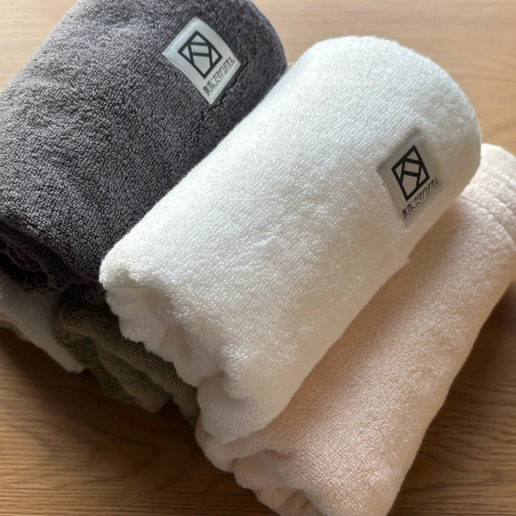 Rolled Senshu hand towels Sawa on a wooden surface.