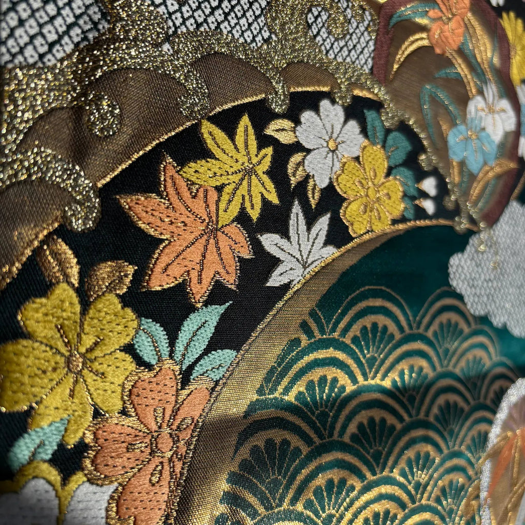 Close-up of embroidered fabric with floral and leaf patterns on a teal background