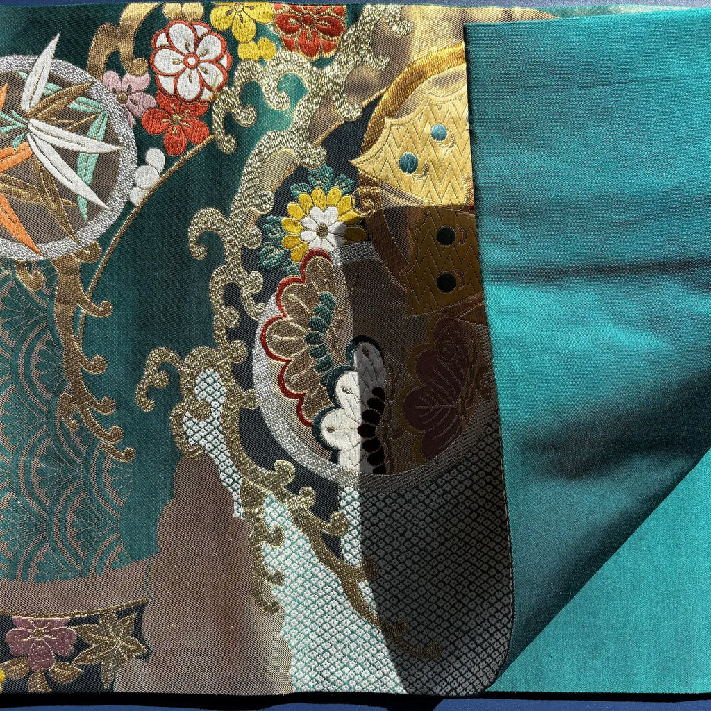 Close-up of embroidered fabric with floral patterns on a teal background