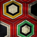 A close-up of a colorful geometric textile pattern featuring hexagonal motifs in red, yellow, green, black, and gold.