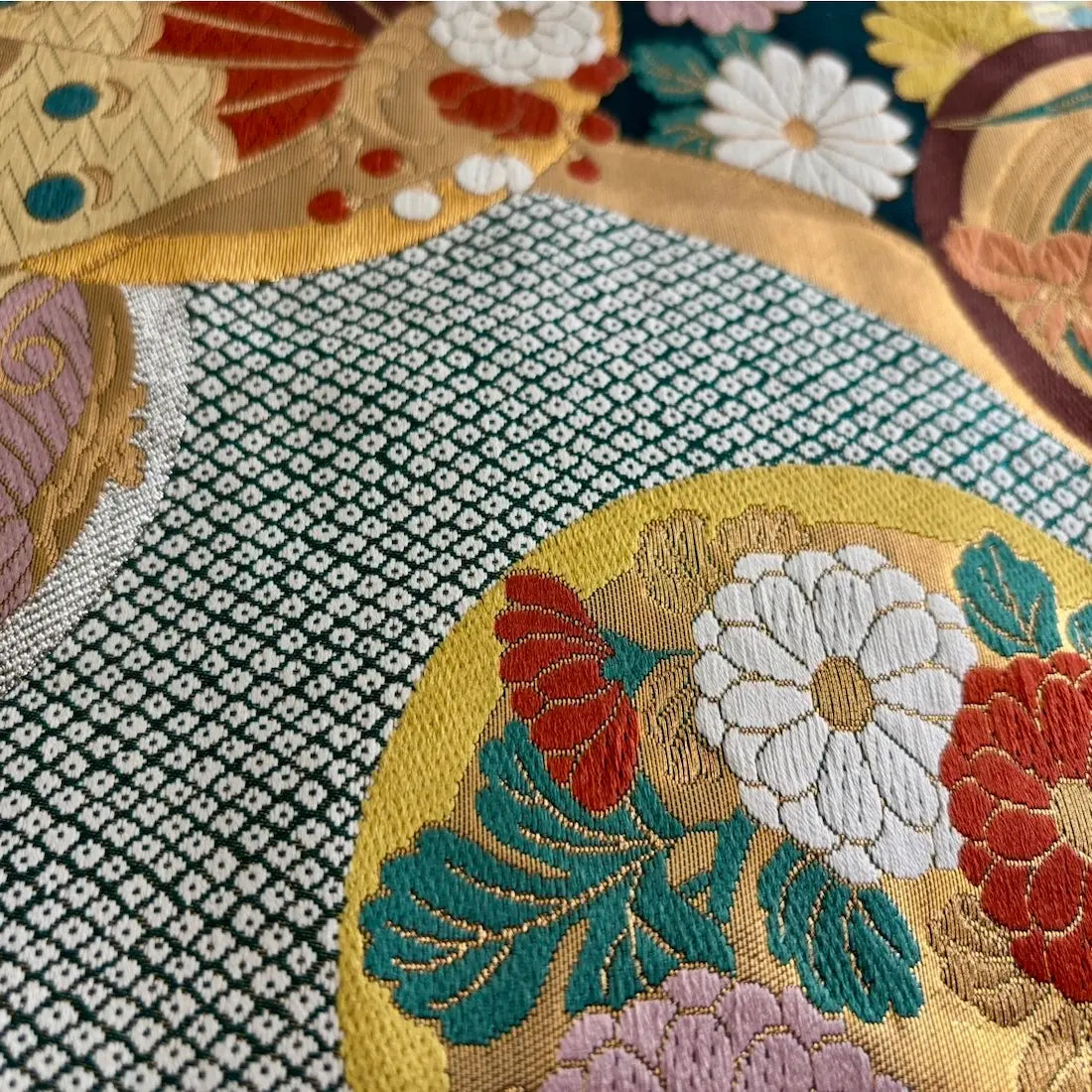 Close-up of a textured fabric with floral embroidery and geometric patterns.