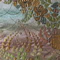 Close-up of embroidered floral pattern with gold, green, and brown colors on a fabric.