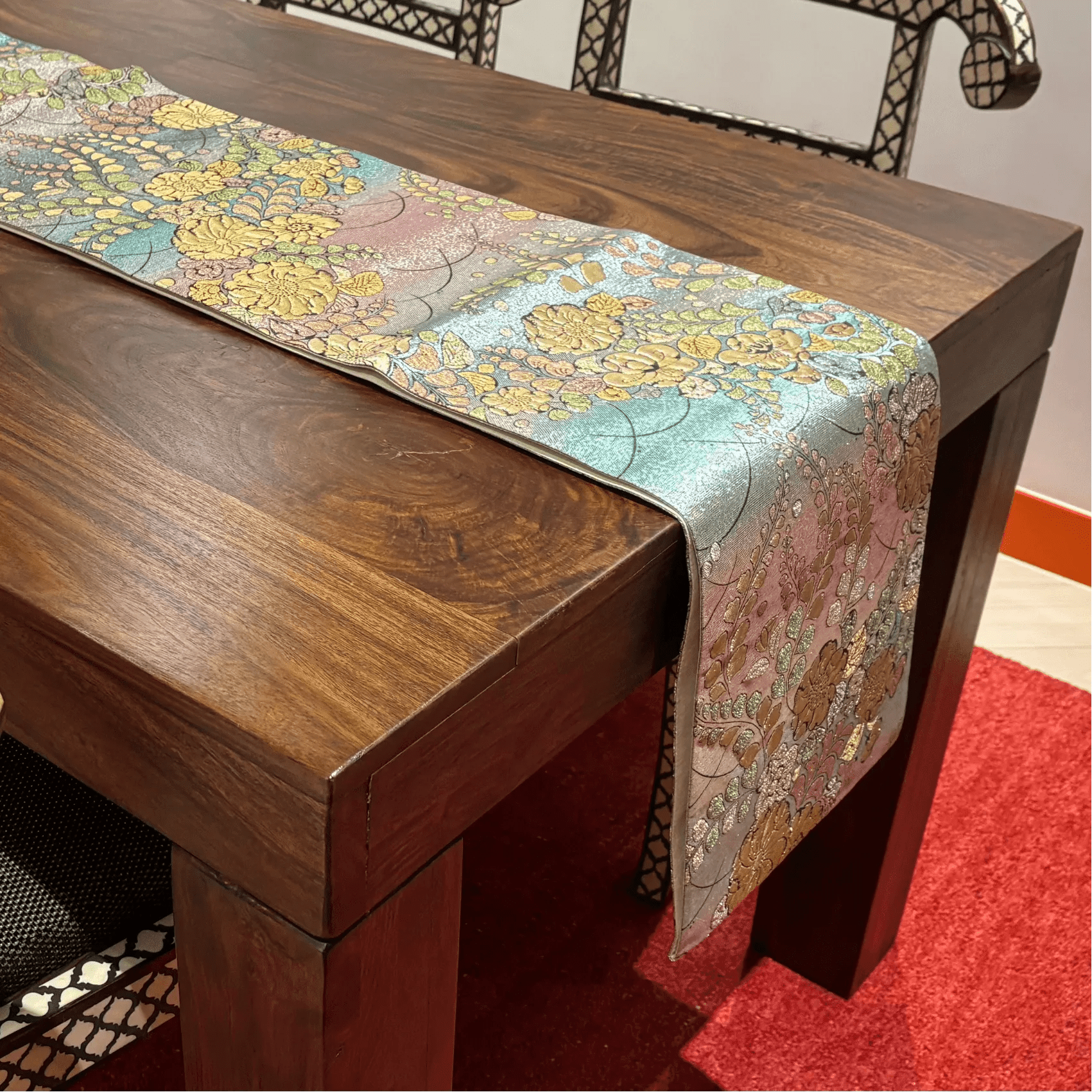 Wooden table with a floral-patterned table runner on a red carpet