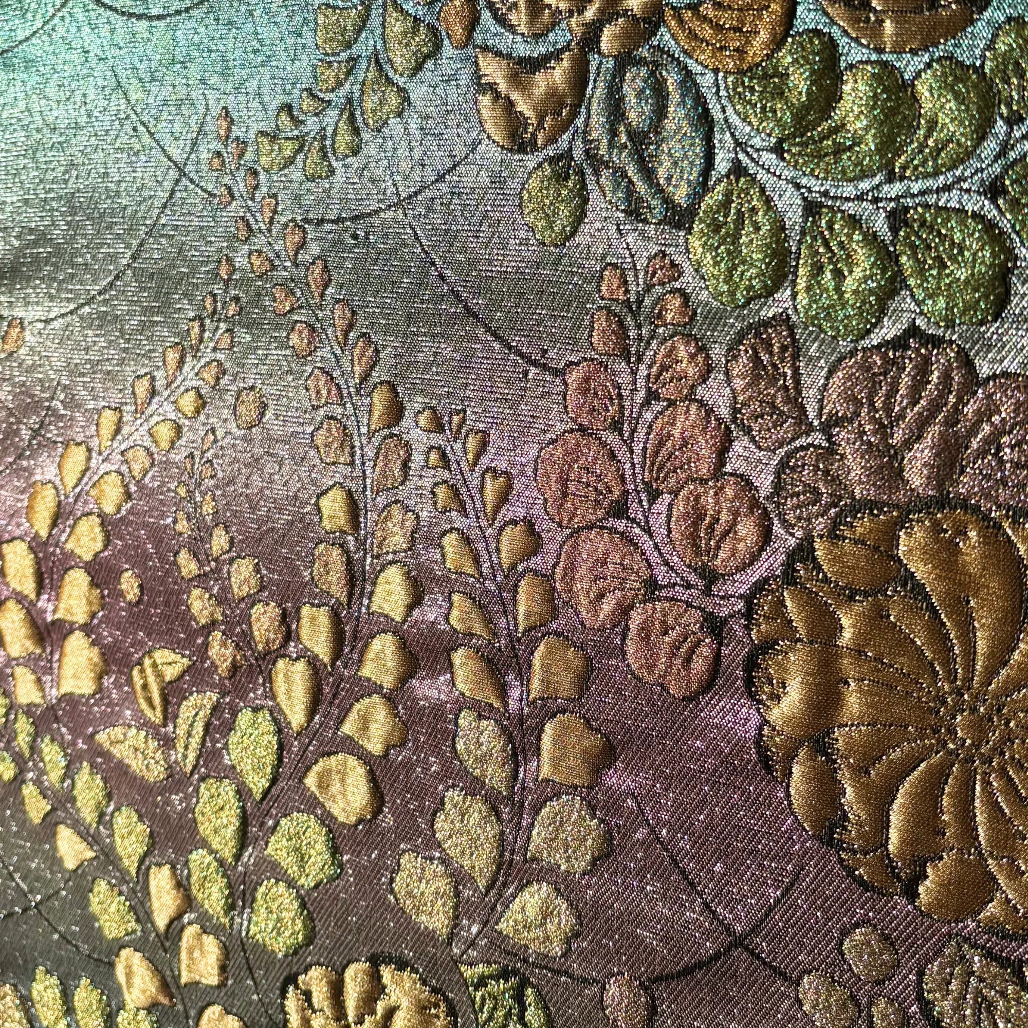 Close-up of an embroidered fabric with floral patterns in gold, green, and brown.