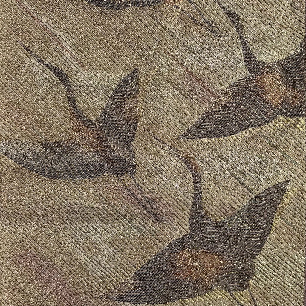 Close-up of embroidered crane on fabric with a gold and beige color scheme.