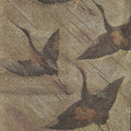 Close-up of embroidered crane on fabric with a gold and beige color scheme.